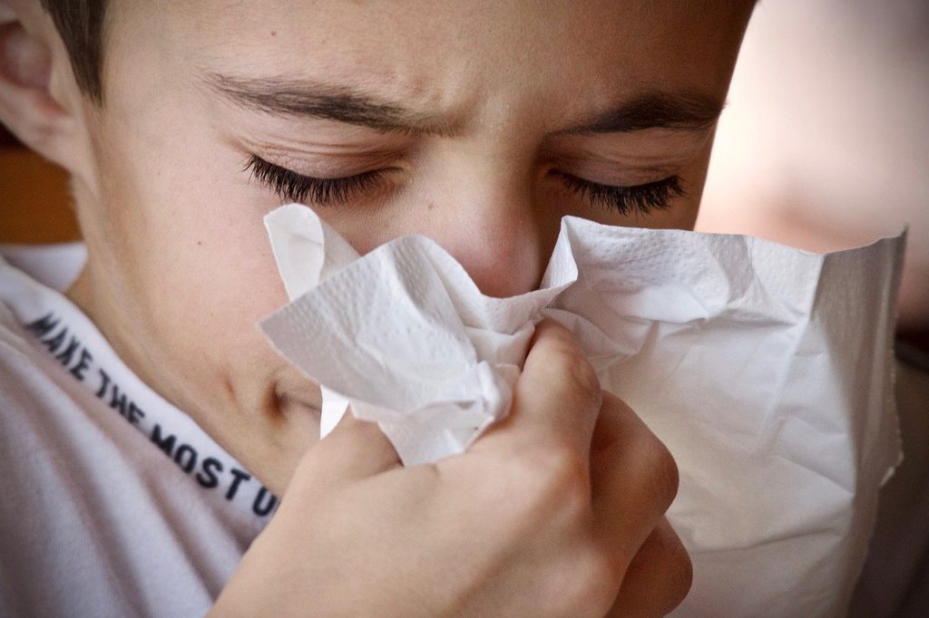 girl sneezing into tissue